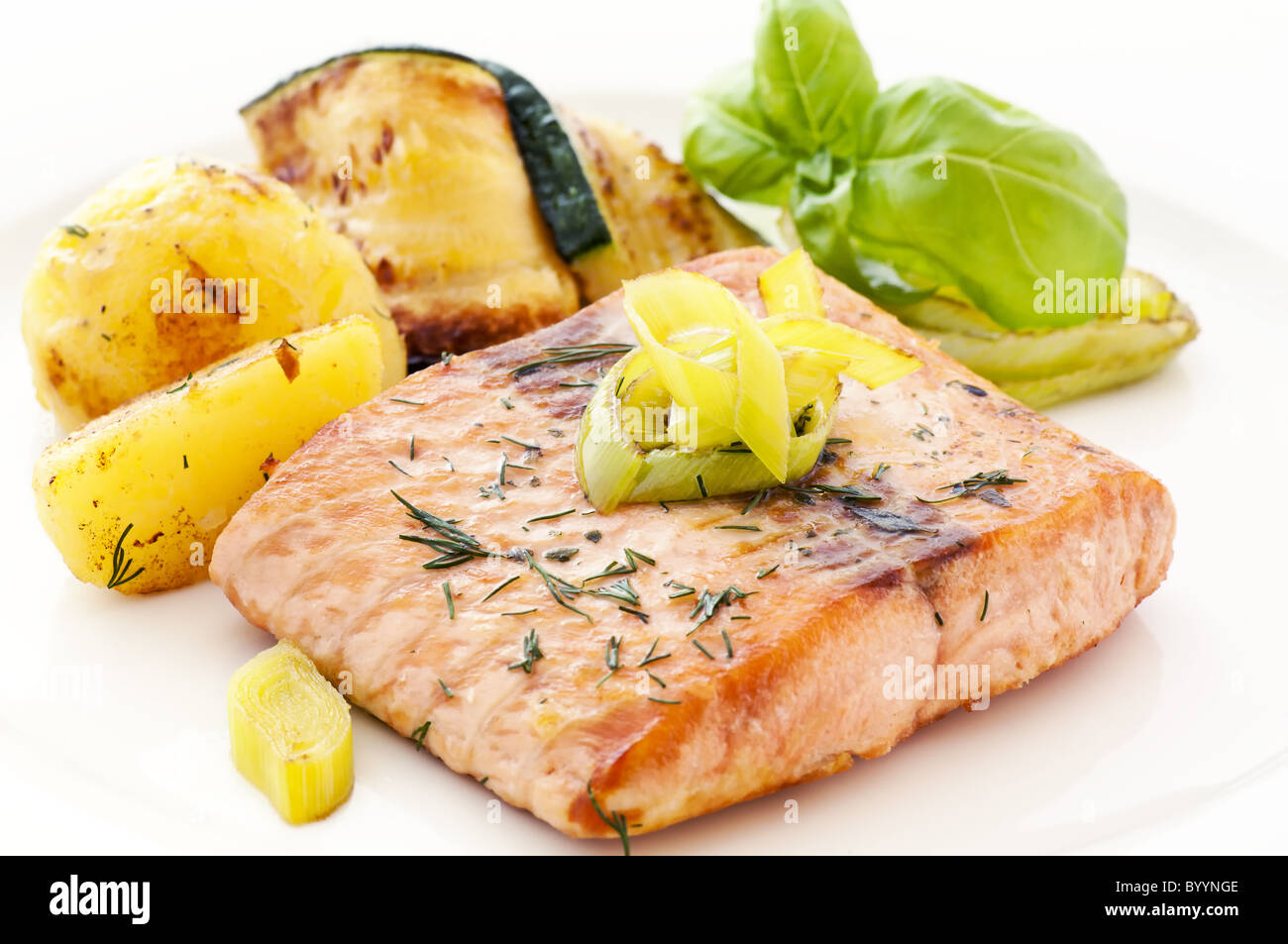 Salmon steak with roast potatoes and zucchini slices as closeup on ...