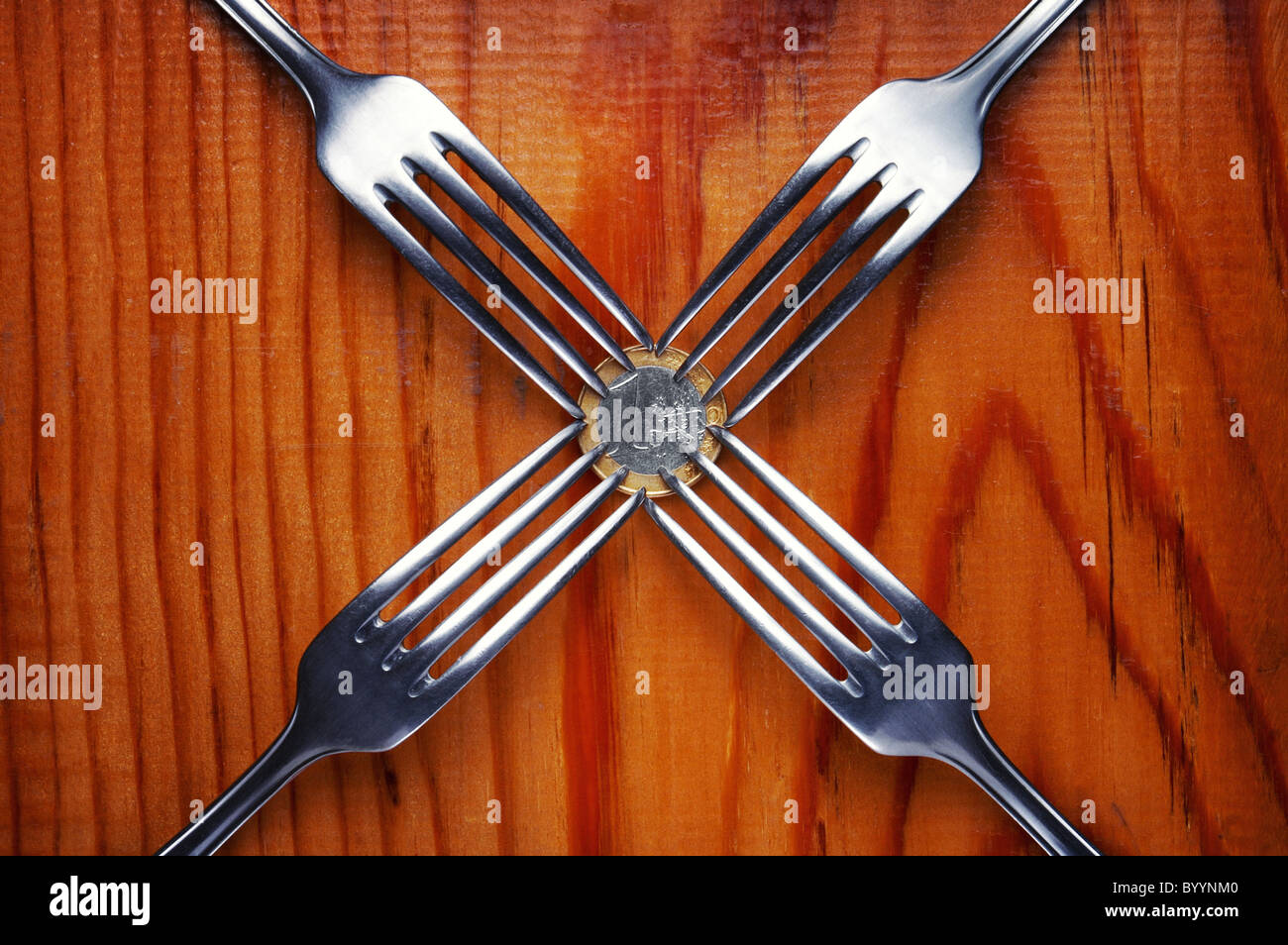 Four forks fighting over one euro coin , financial crisis competition ,wood background Stock Photo