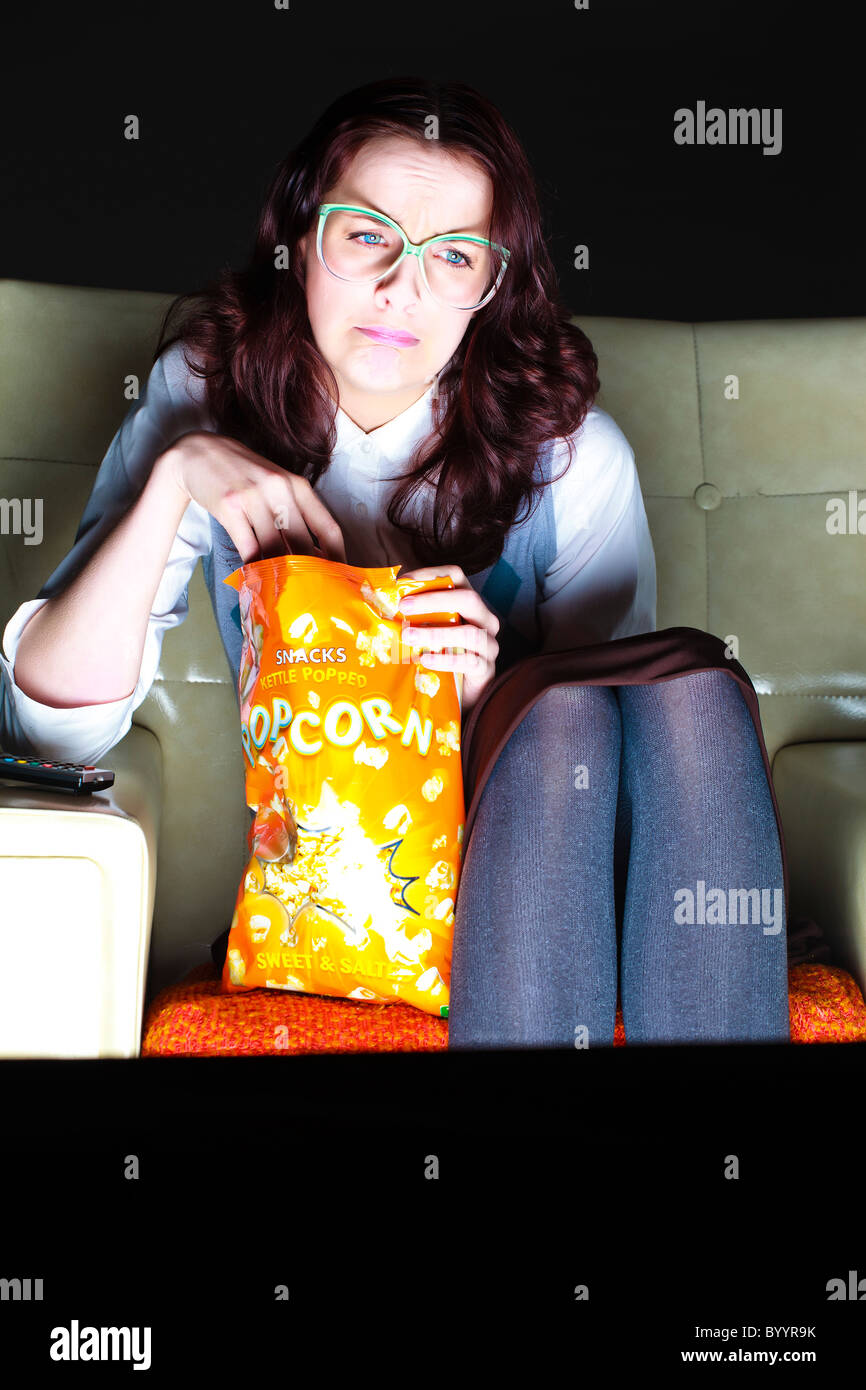 Geeky girl eating popcorn upset watching television Stock Photo Alamy