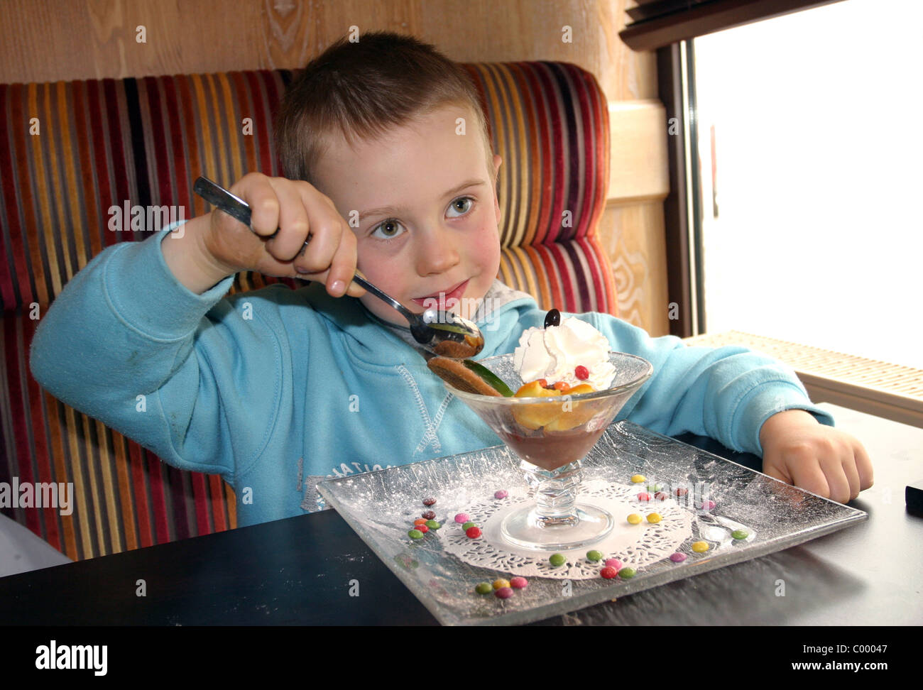 Young boy eating a peach melba dessert Stock Photo