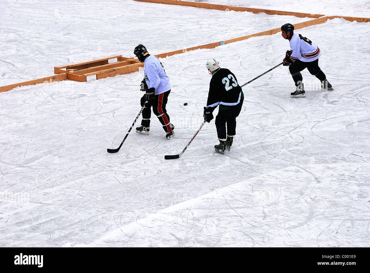 Three adult amateur hockey players in 'Pond Hockey' game Stock Photo