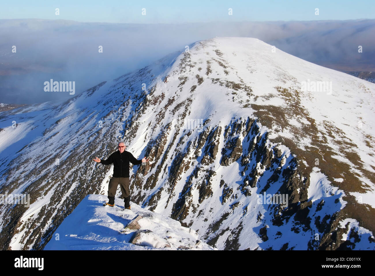 Hiker enjoying the experiance on Stob Coire Easian with Stob a'Choire Mheadhoin in the background. Stock Photo