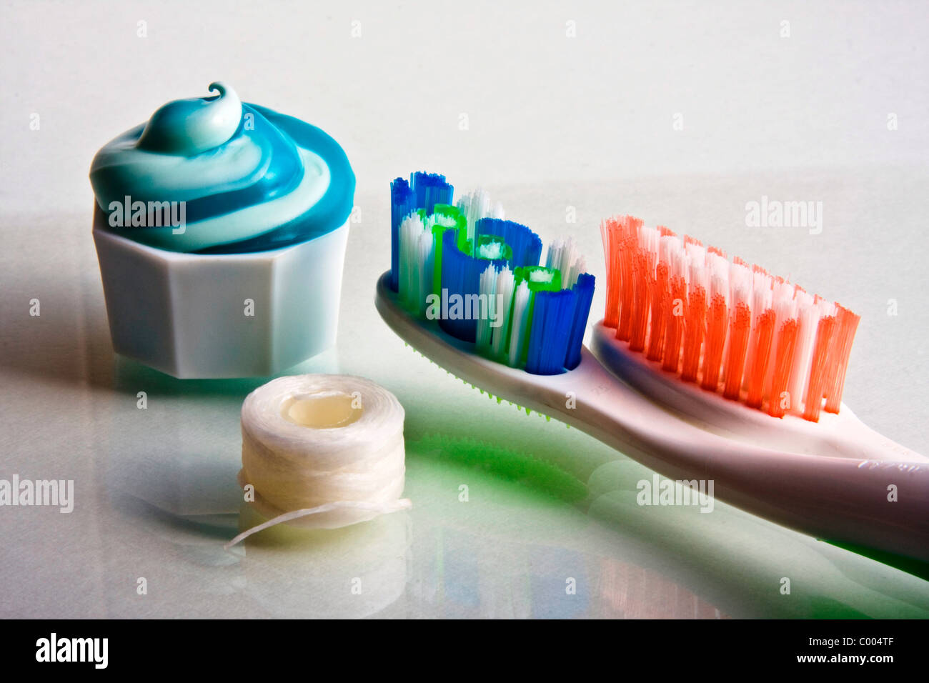 Toothpaste squeezed from tube onto cap with toothbrushes and floss