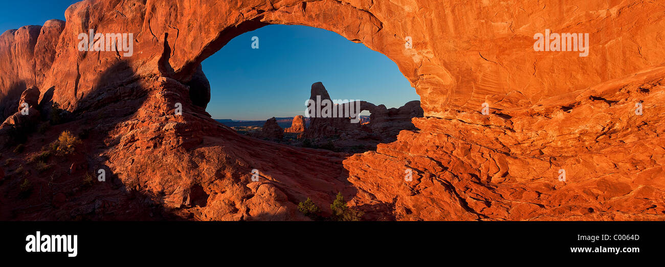 A panoramic image of Turret Arch as seen through North Window at sunrise, Arches National Park, Utah, USA. Stock Photo