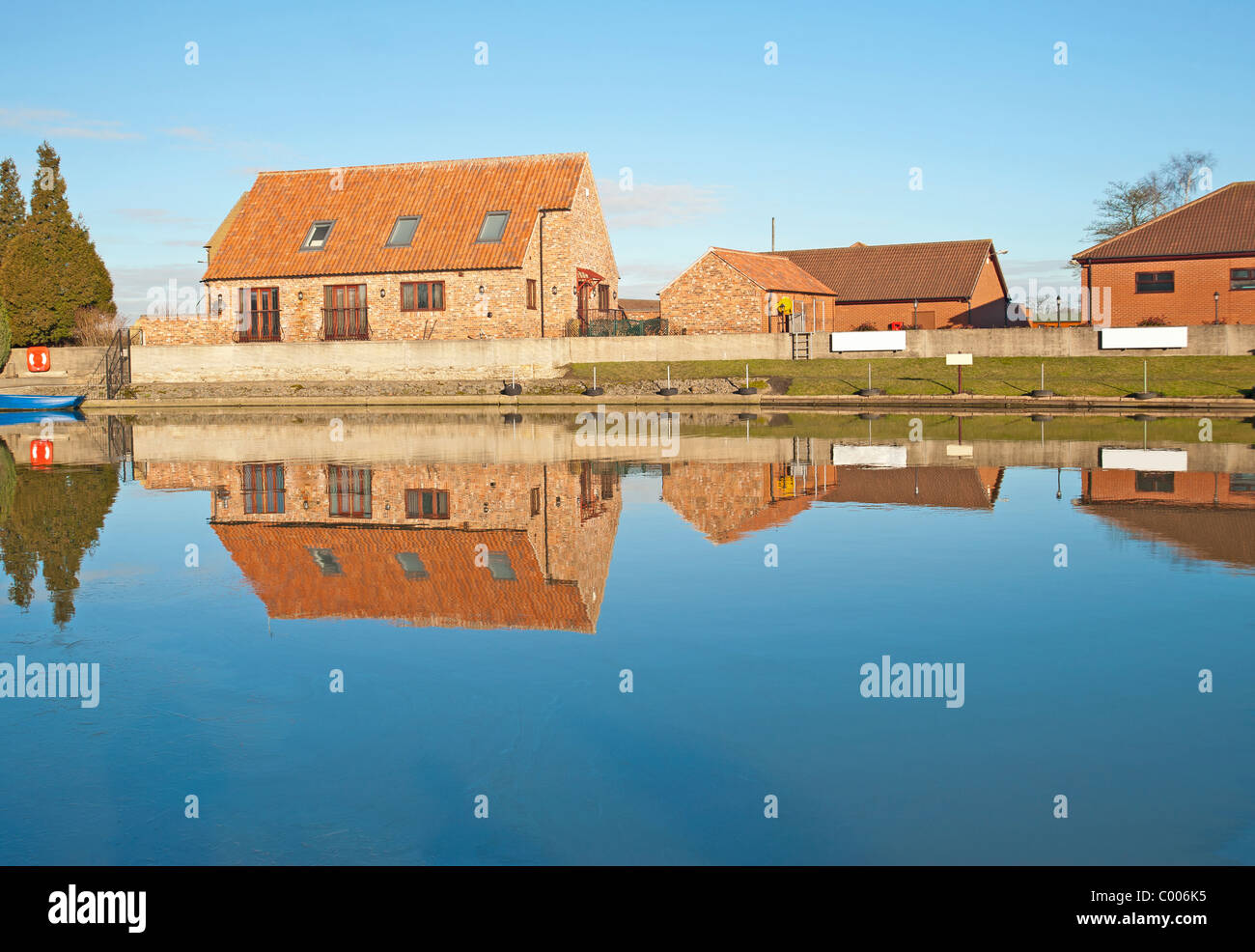 Houses in the countryside next to a small river with reflection Stock Photo