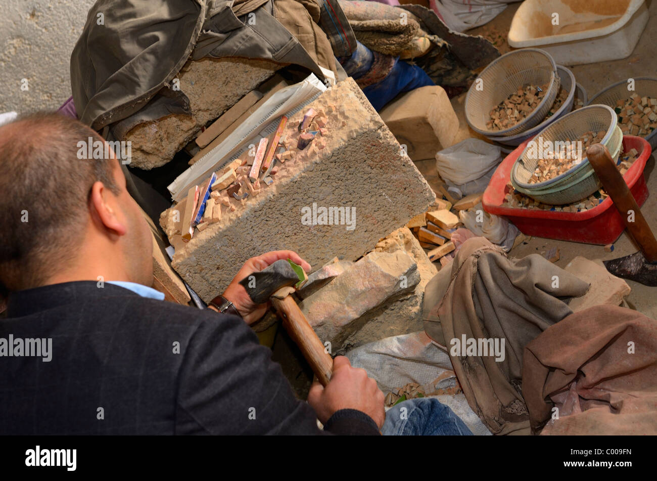 Craftsman freehand chiseling glazed terra cotta pieces for Zellige tilework in workshop of Fez Morocco North Africa Stock Photo