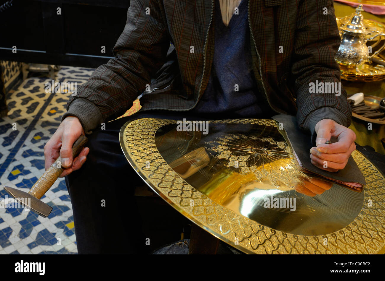 Worker with hammer and chisel showing work in progress engraving brass