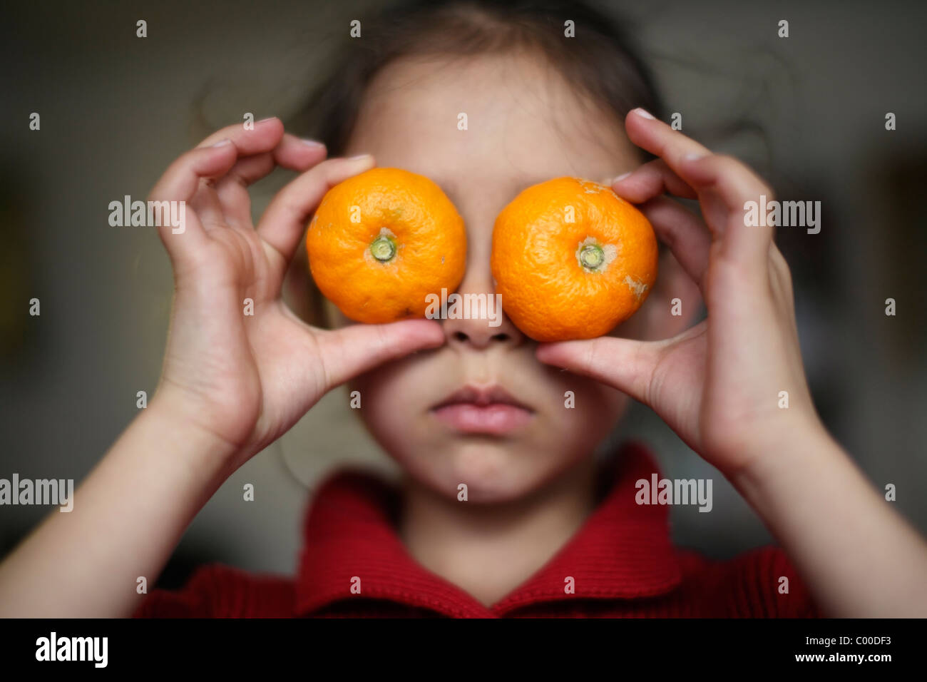 Girl holds oranges over her eyes. Stock Photo