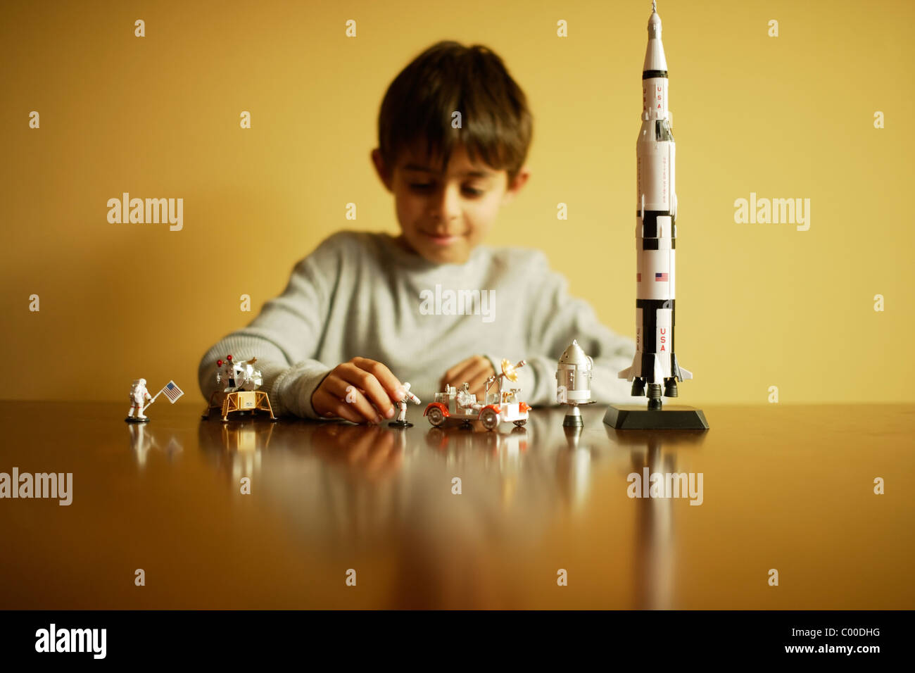 Boy with model Saturn V Apollo moon rocket, astronauts, lunar module and lunar rover. Stock Photo