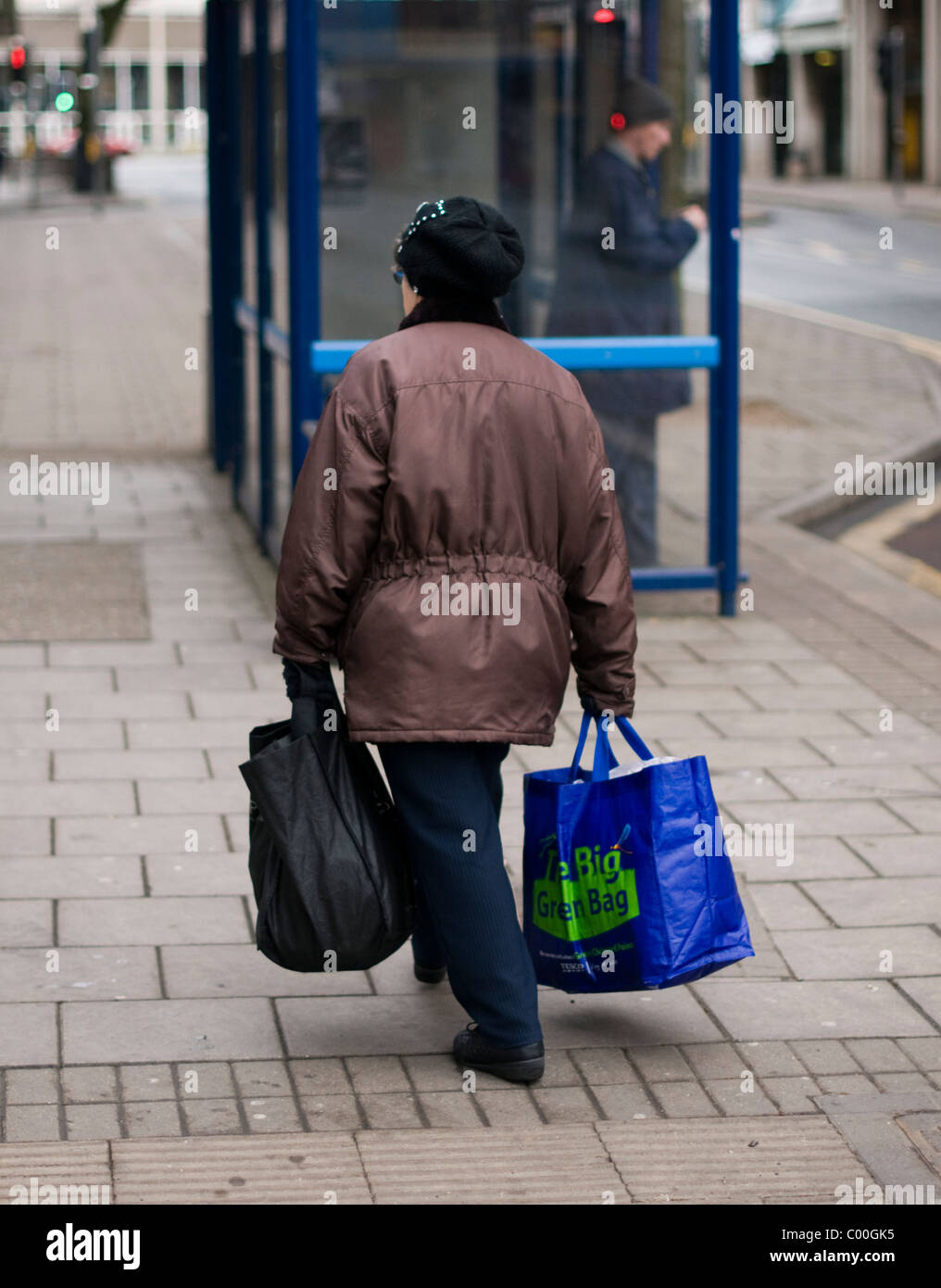 Old lady carrying heavy shopping bags through Coventry city center, UK. Stock Photo