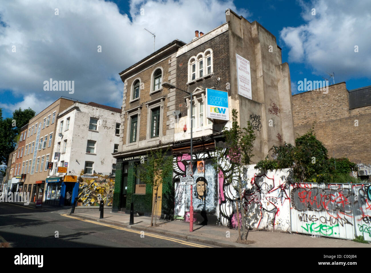 The green tiled Labour and Wait pub next to derelict shop and boarded up site with graffiti in Redchurch Street near Brick Lane Stock Photo