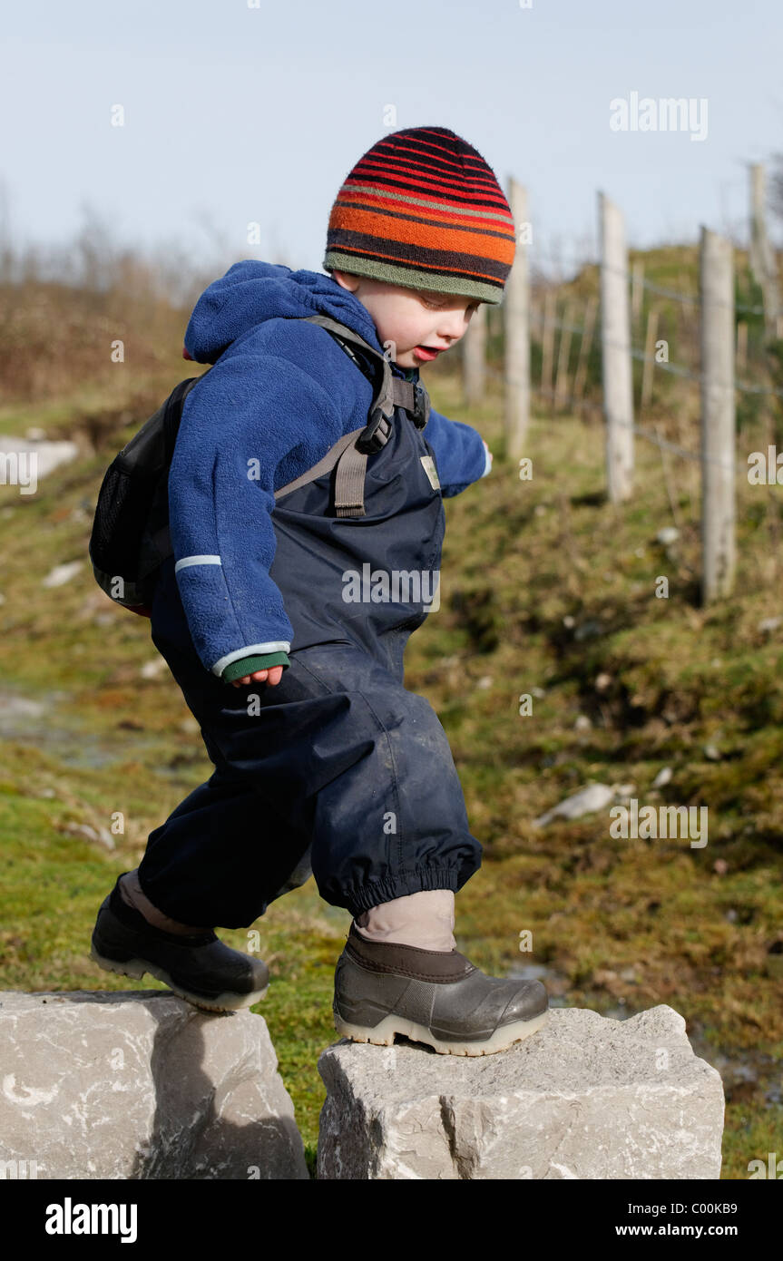 A young boy jumping between two large stones Stock Photo - Alamy
