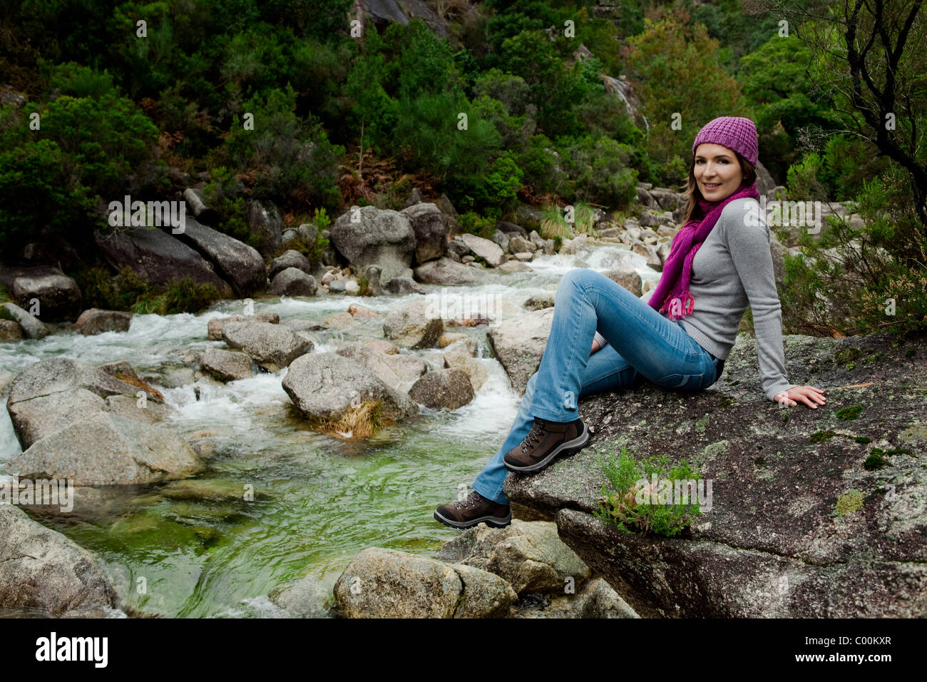 Outdoor portrait of a beautiful young woman sitting on a rock Stock ...