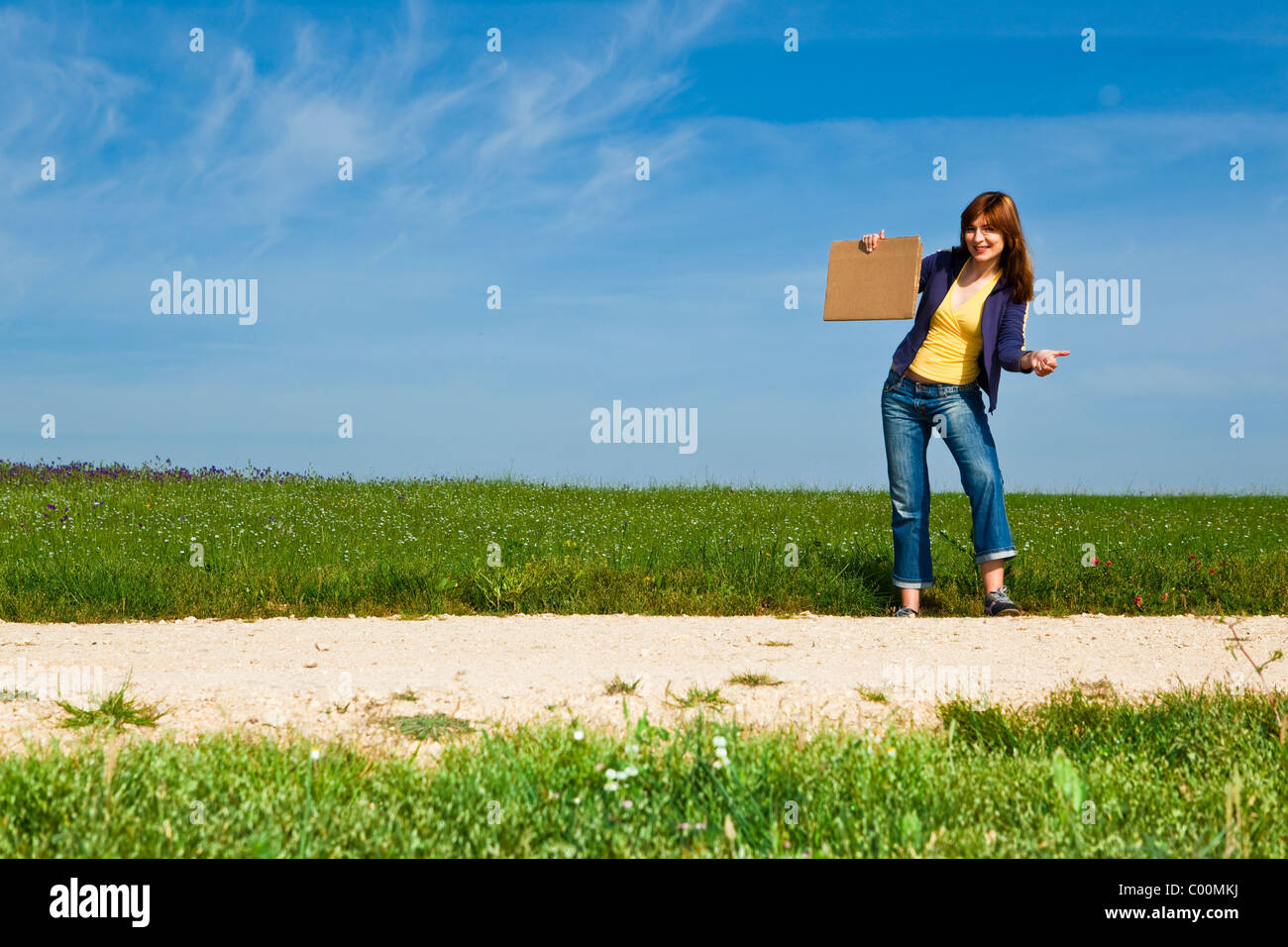 Young woman hitch hiking on a beautiful green meadow Stock Photo Alamy