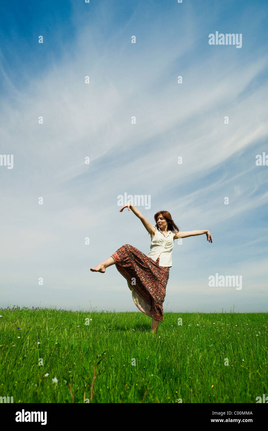 Young woman making dancing poses on a beautiful green meadow Stock Photo