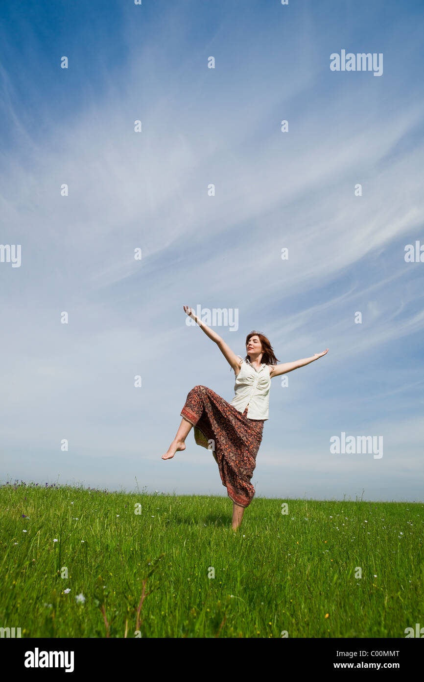 Young woman making dancing poses on a beautiful green meadow Stock Photo