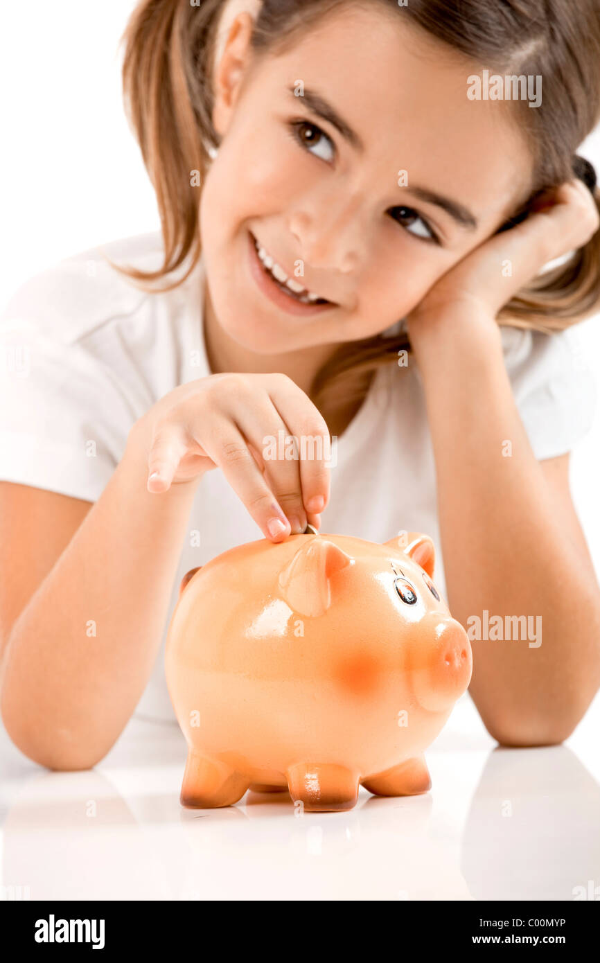 Little girl lying on floor and inserting a one euro coin on the piggy ...
