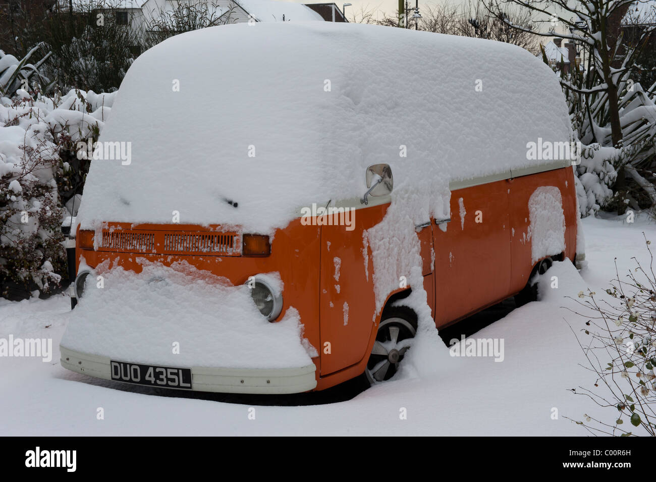 A snowed under orange Volkswagen Camper van Stock Photo