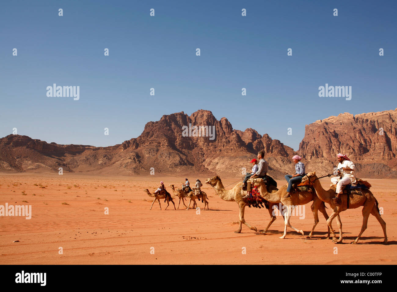 Tourists riding camels in the desert, Wadi Rum, Jordan. Stock Photo