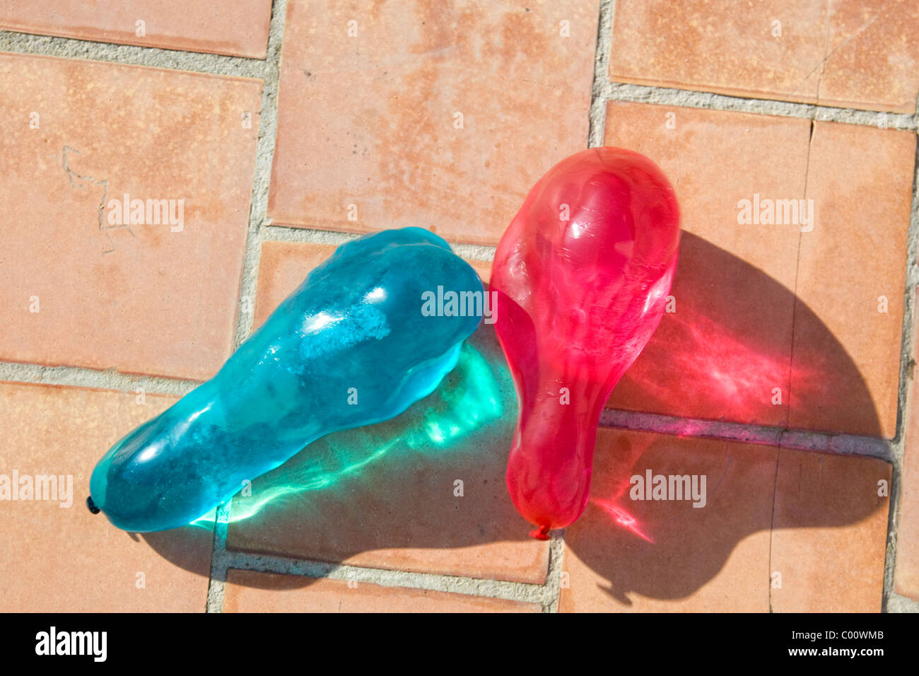 Two water filled colored balloons crashing against the floor Stock Photo