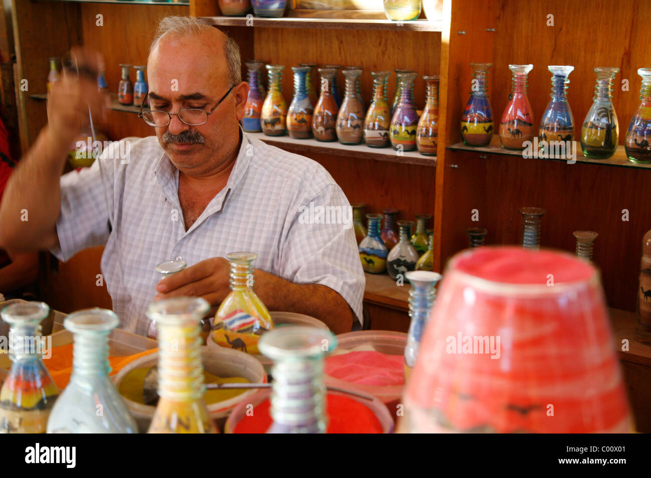 An artist filling souvenir bottles with desert sand, Jerash, Jordan. Stock Photo