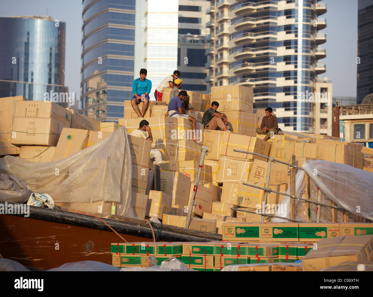 Workers sit atop a mountain of cardboard boxes in the evening sun in