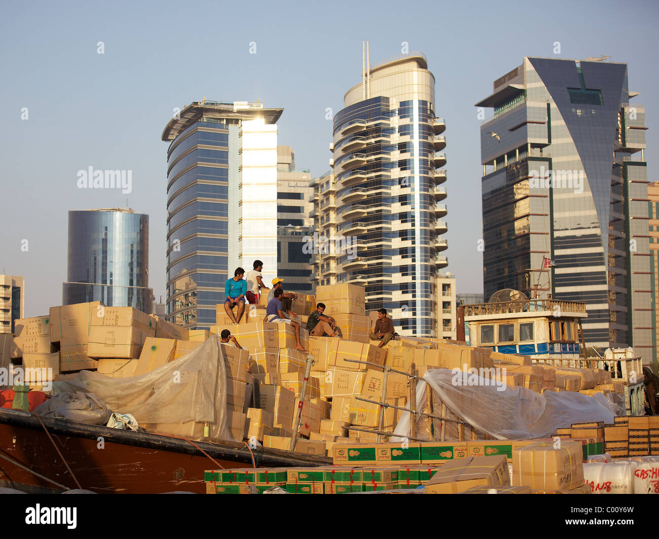 Workers sit atop a mountain of cardboard boxes in the evening sun in