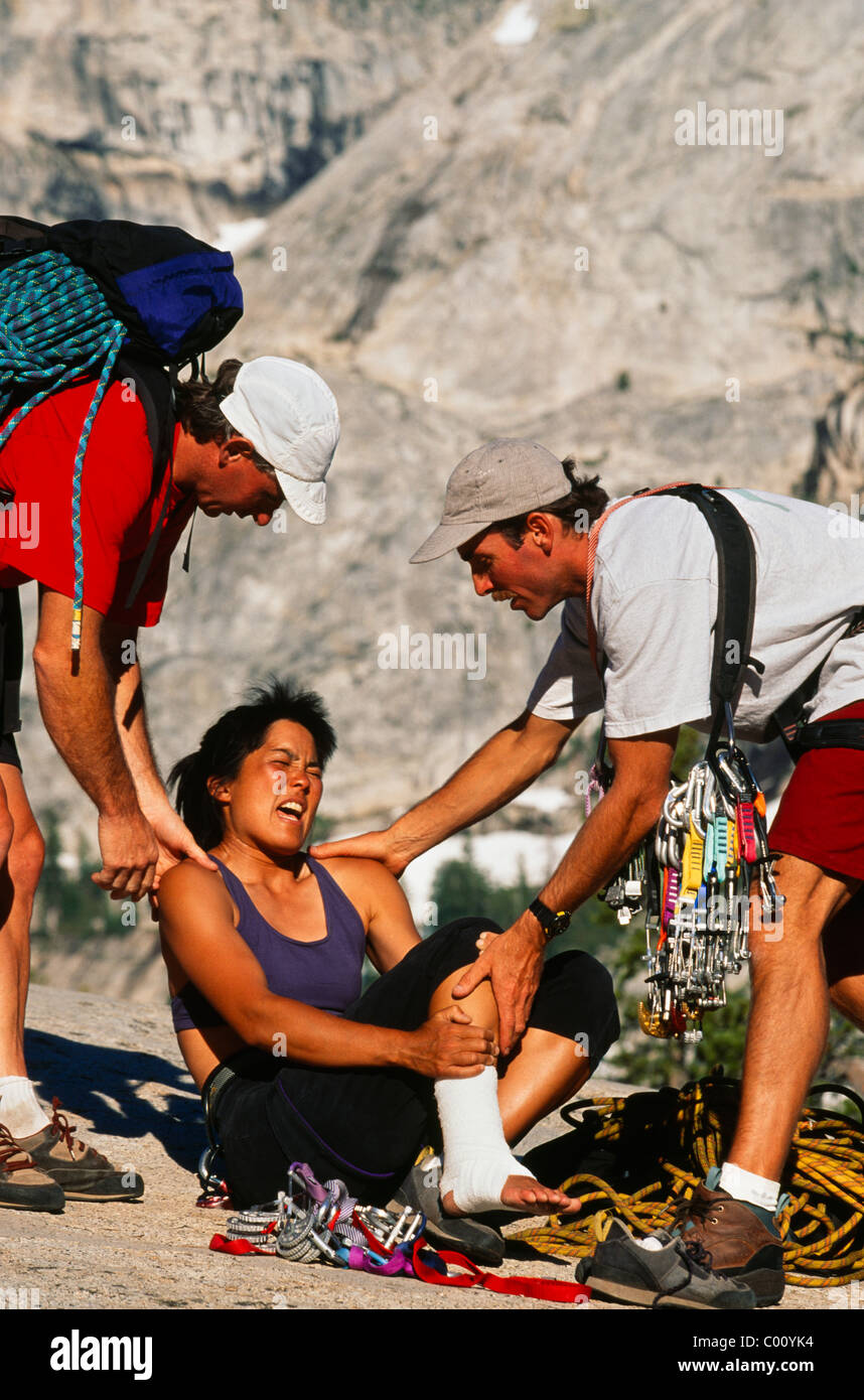 Team of climbers give first-aid and carry their injured partner out of the wilderness. Stock Photo