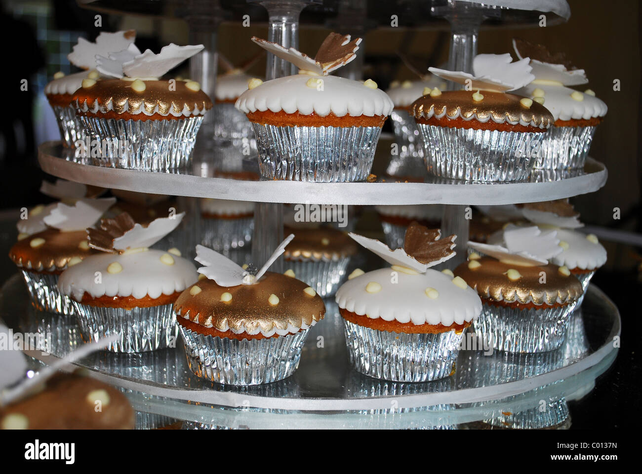 A Plate Of Cup Cakes In Silver Cases With White Icing And Butterfly Decoration On Tiered Cake Stand UK 2008 A Plate Of Cup Cakes In Silver Cases With White Icing And Butterfly Decoration On Tiered Cake Stand UK 2008