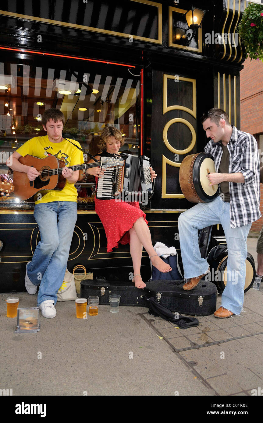 Making music with an accordion, a guitar and a frame drum at an Irish music session in the street, music festival Fleadh Cheoil Stock Photo