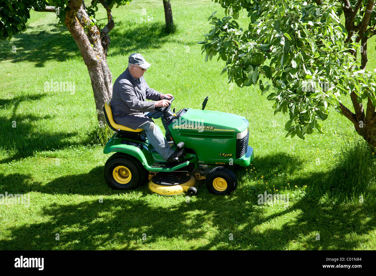 Elderly man mowing the lawn on a John Deere sit-on lawnmower, Bengel, Rhineland-Palatinate, Germany, Europe Stock Photo