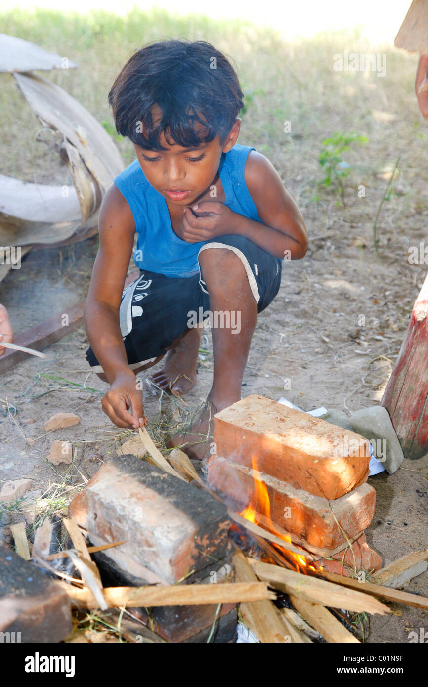 Boy lighting a fire and cooking on a hearth, Fortaleza, Ceará, Brazil, South America Stock Photo