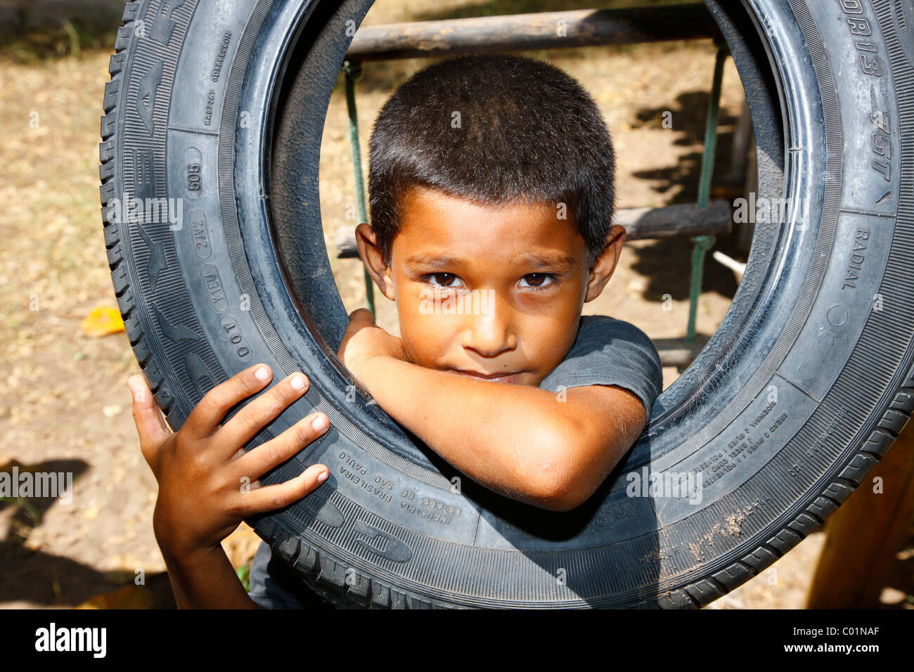 Boy looking through a car tyre, Fortaleza, Ceará, Brazil, South America Stock Photo