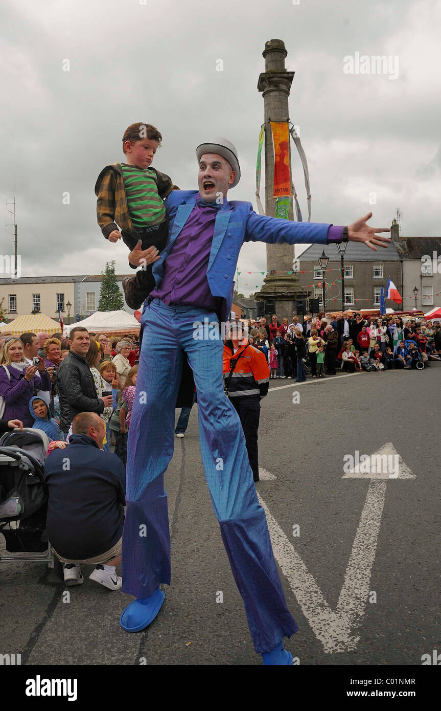 Stilt walker holding a child at the parade of the town festival in Birr