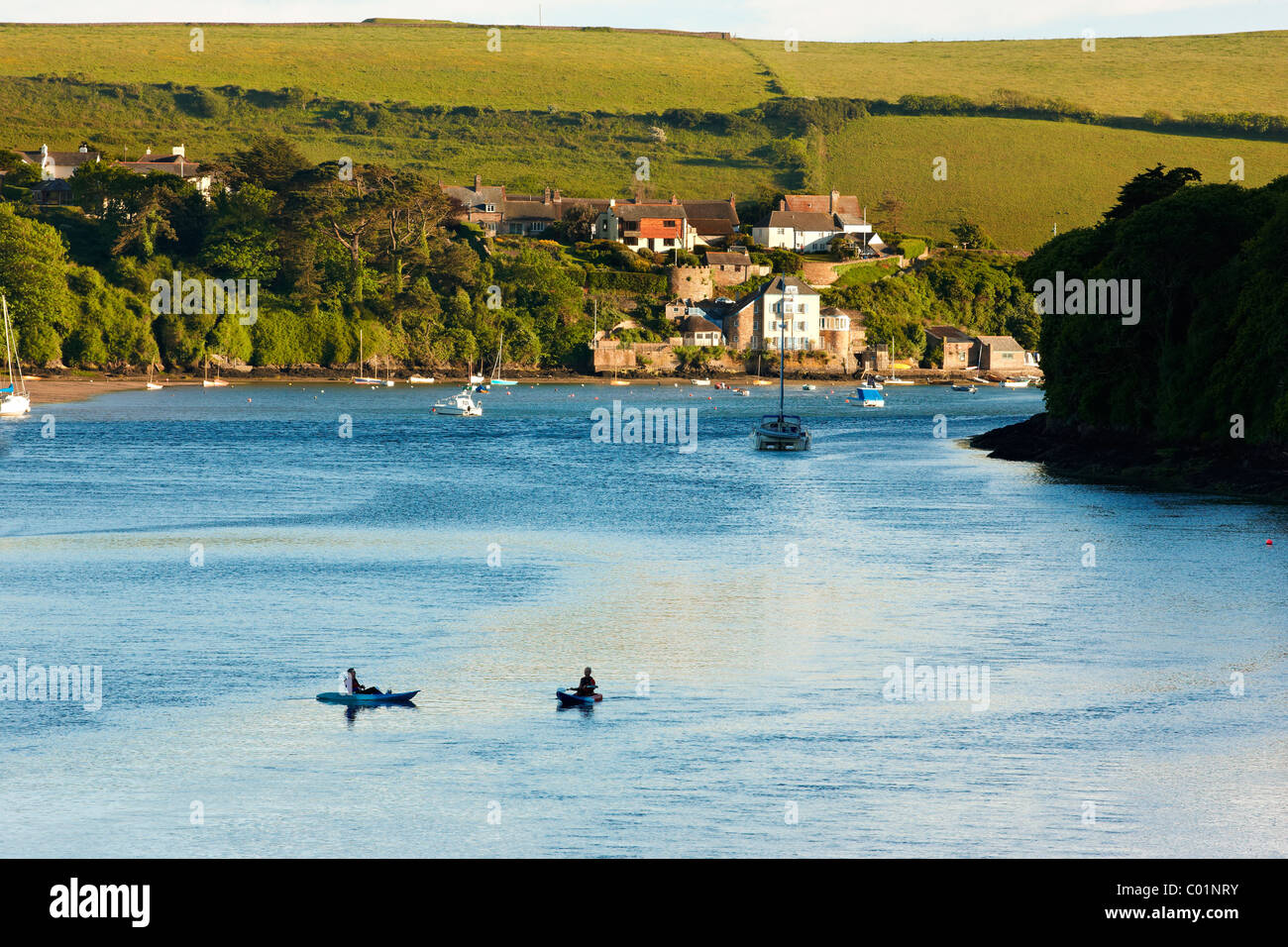 Canoeists on a summer's evening on the Avon estuary with the village of Bantham in the background. Devon UK Stock Photo