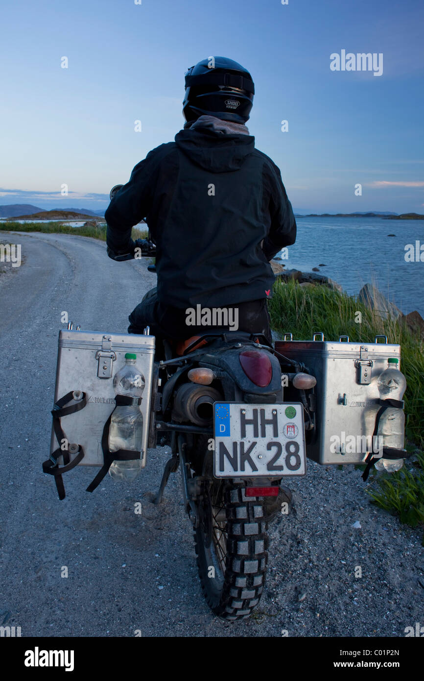 Man riding an Enduro motorcycle along the Norwegian coast in the evening twilight, Gimsefjorde, Norway, Scandinavia, Europe Stock Photo