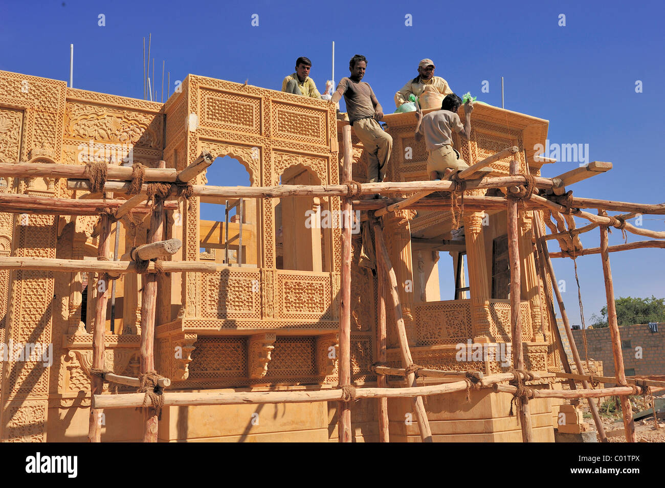 Craftsmen working on a simple wooden frame with knotted ropes on an ornate sandstone facade, Jaisalmer, Rajasthan, India, Asia Stock Photo