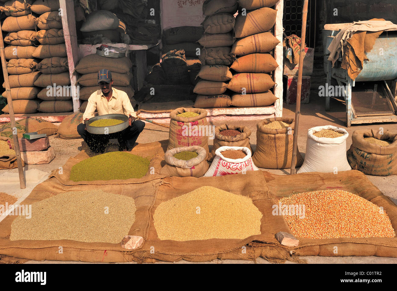 Grain merchant sieving grain at the grain markets, in front of him