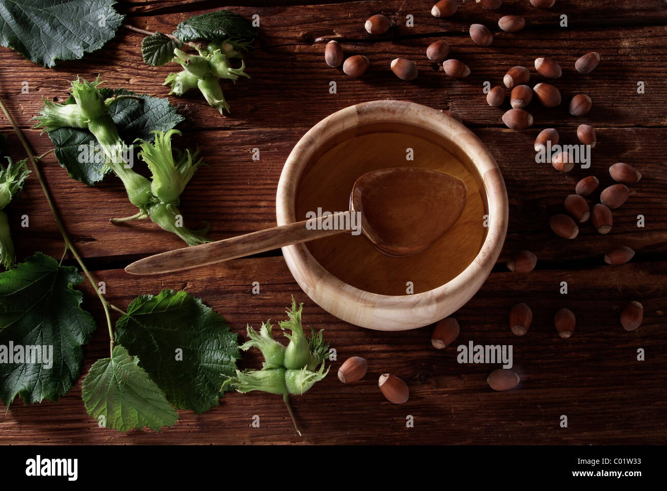 A bowl of hazelnut oil and some ripe and unripe hazelnuts (Corylus