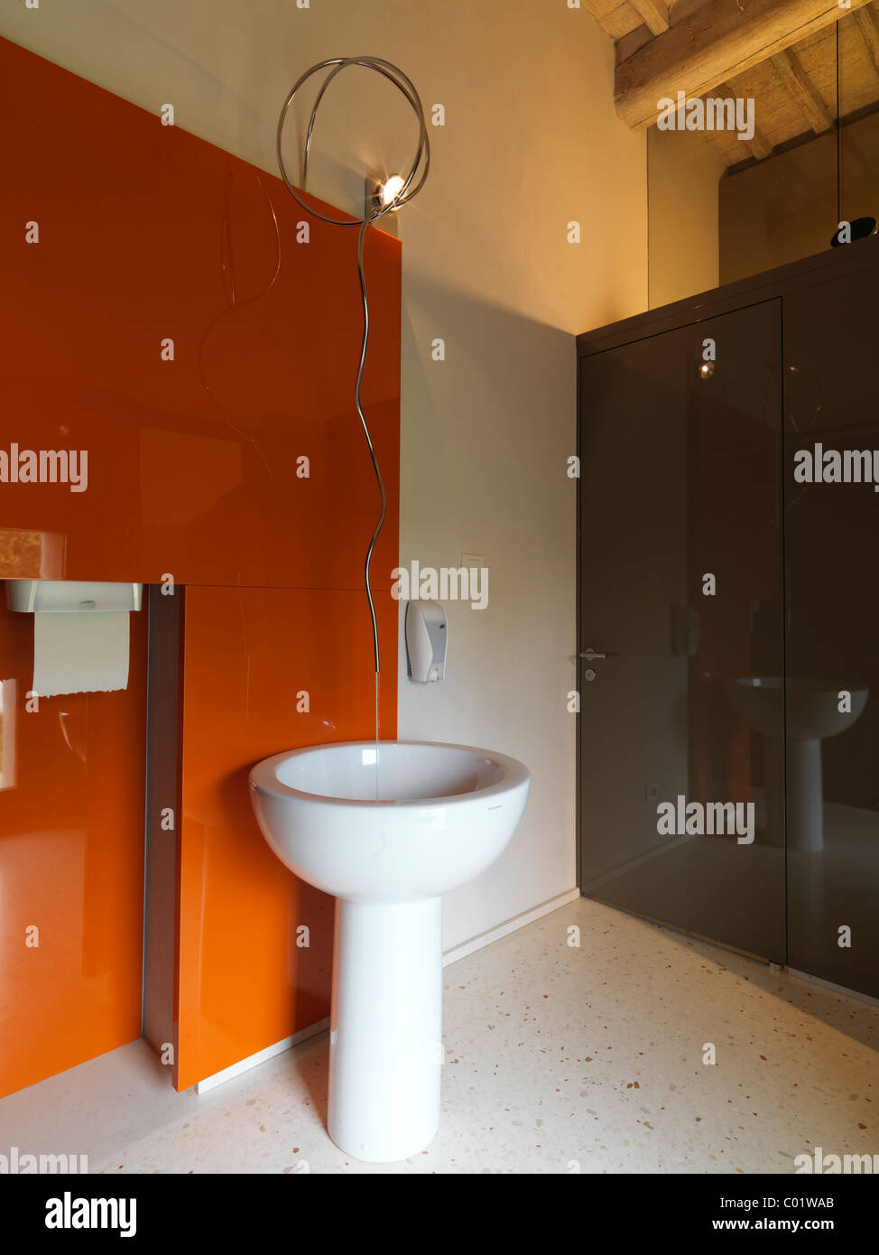 elegant and modern bathroom with orange wall and white ceramic washbasin at column Stock Photo