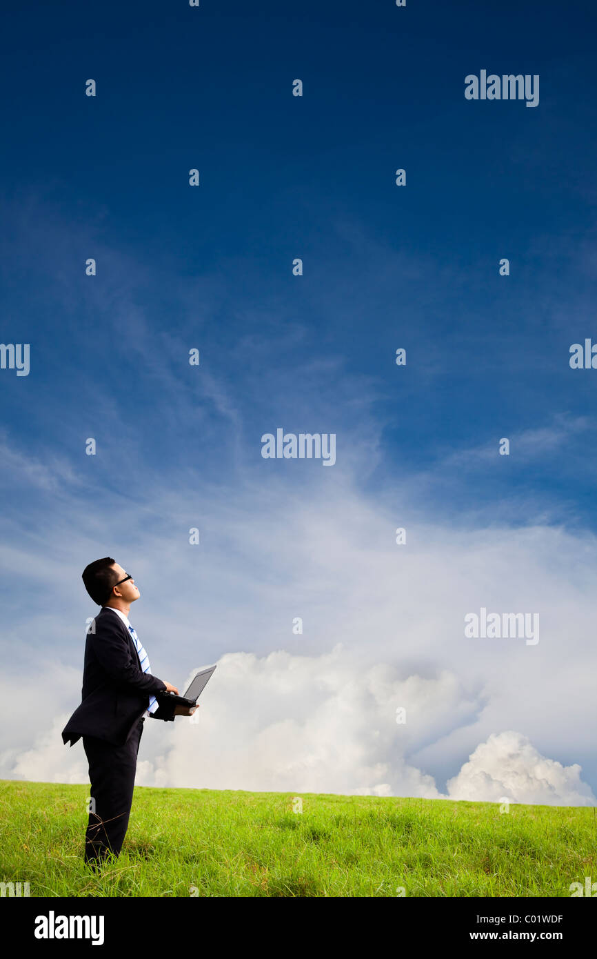 Businessman holding computer and watching the cloud Stock Photo