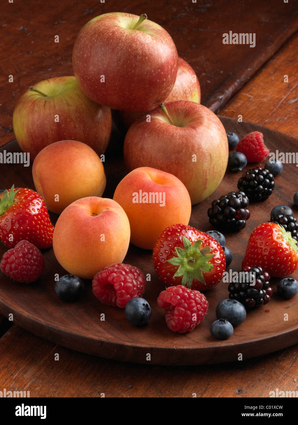 A pile of fresh ripe fruit apples strawberries blueberries blackberries raspberries and apricots Stock Photo