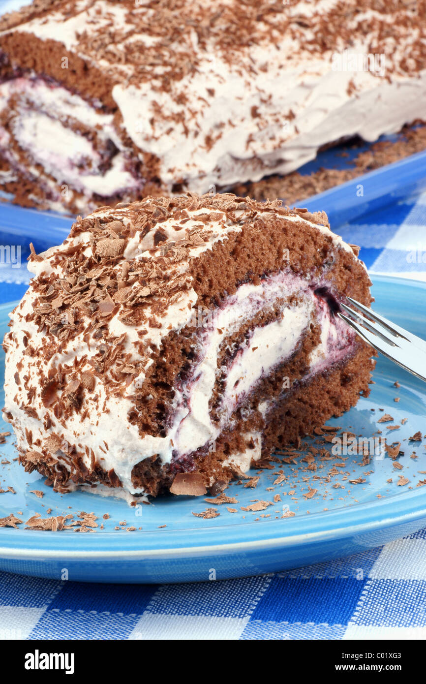 Chocolate swiss roll cake with berries marmalade and whipped cream over a chequered background