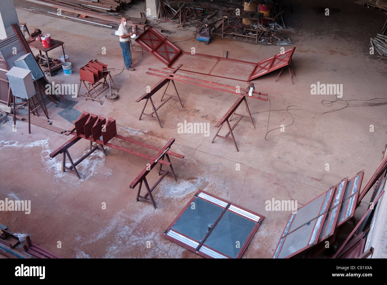 A sheet metal worker sprays some doors with red oxide paint, Las