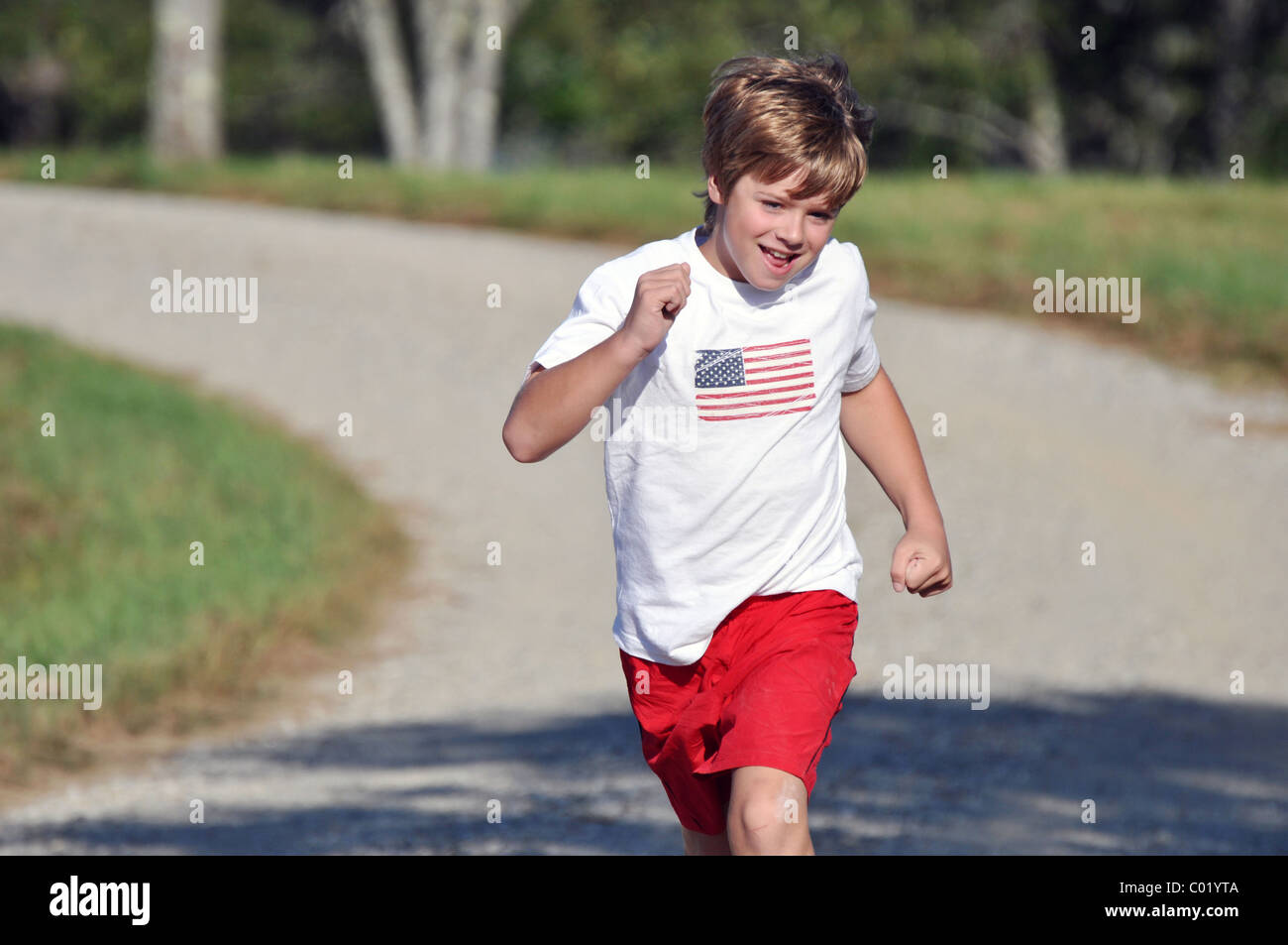 11 year old boy running up road Stock Photo