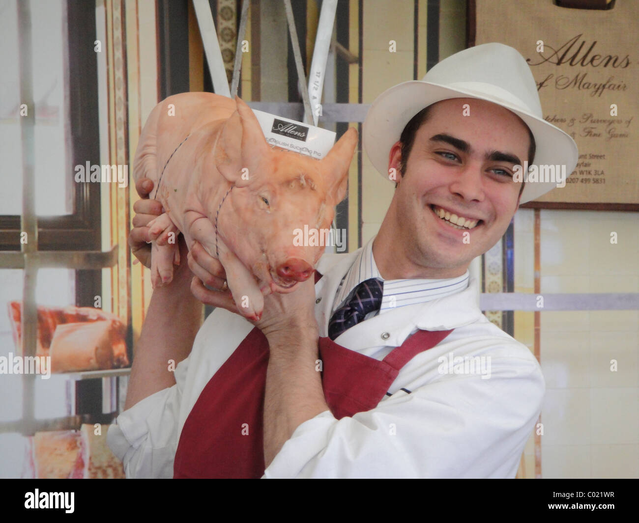 Butcher holding a whole piglet at a food show Stock Photo