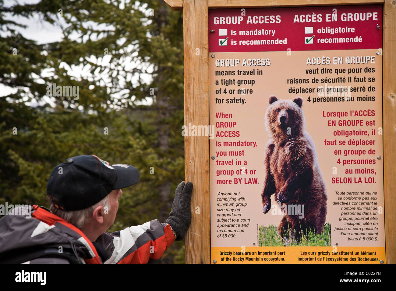 Man looking at a bear warning sign on the trail to Consolation Lake near Moraine Lake Banff National Park Alberta, Canada Stock Photo