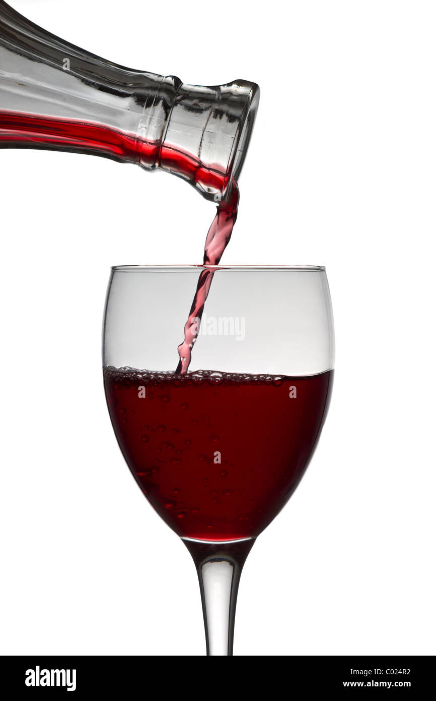 red wine pouring down from a wine decanter into a wine glass on white