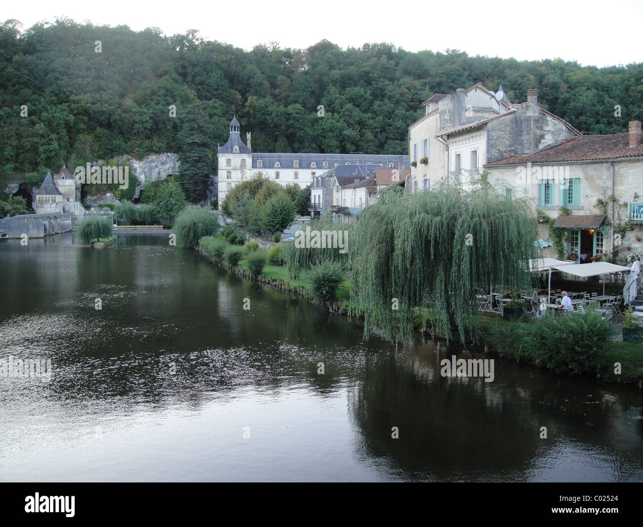 Riverside view of River Donne at Brantôme with houses and restaurant and the Abbey of Brantôme in the background Stock Photo