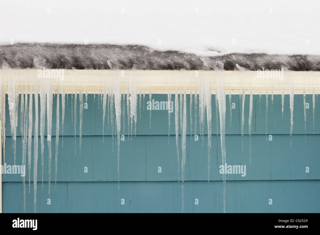 gutter ice dam and icicles damage a roof Stock Photo